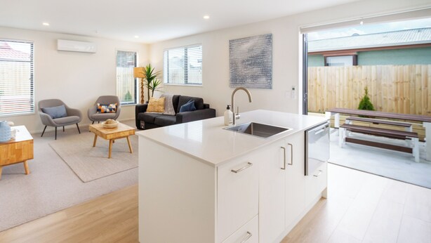Una cocina moderna con una isla grande, un comedor con mesa de madera y una sala de estar con sofá y sillas.