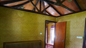 A bedroom with a wooden bed, a ceiling fan, and a door leading to another room. - Korovou Eco Resort (Naviti Island)