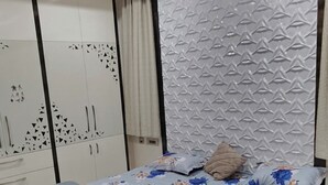A bedroom with a bed, a ceiling fan, a wardrobe, and a textured wall.