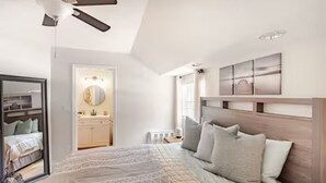 Un dormitorio con una cama, un ventilador de techo, una mesita de noche y una lámpara fijada a la pared.