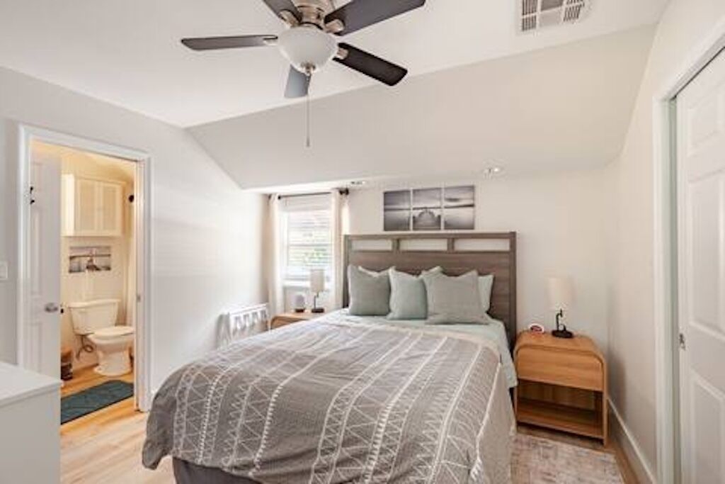 A bedroom with a bed, nightstands, a ceiling fan, and a window.