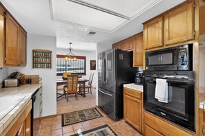 A kitchen with wooden cabinets, a black refrigerator, a microwave, and an oven.