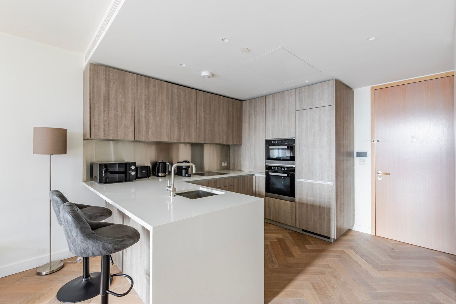 A modern kitchen with a central island, built-in appliances, and a bar stool.