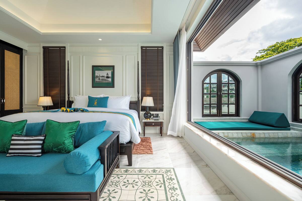 Une chambre d’hôtel avec un grand lit, une vue sur une piscine et une fenêtre donnant sur l’extérieur.
