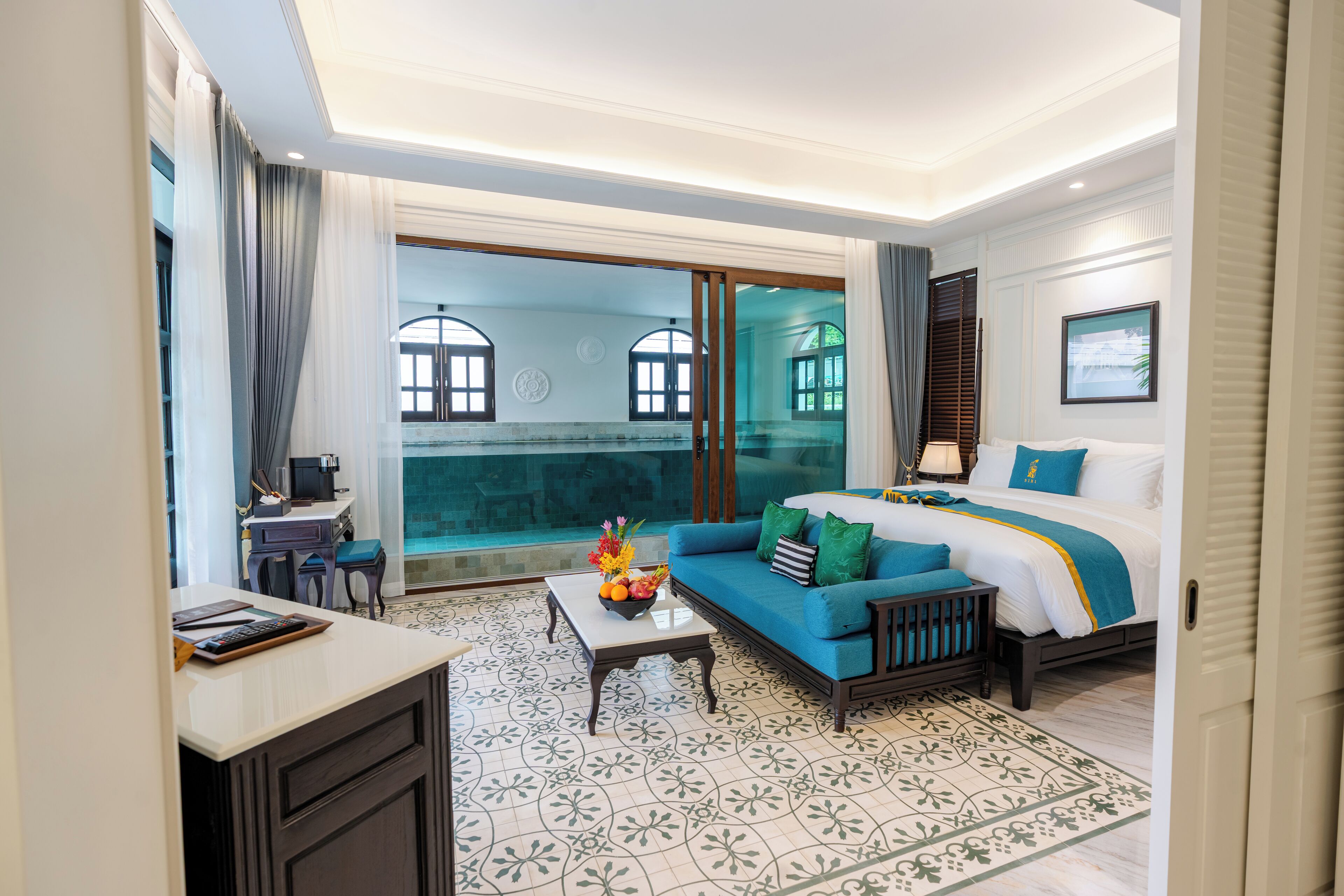 Une chambre d’hôtel avec un lit, un canapé, un bureau et une vue sur la piscine.
