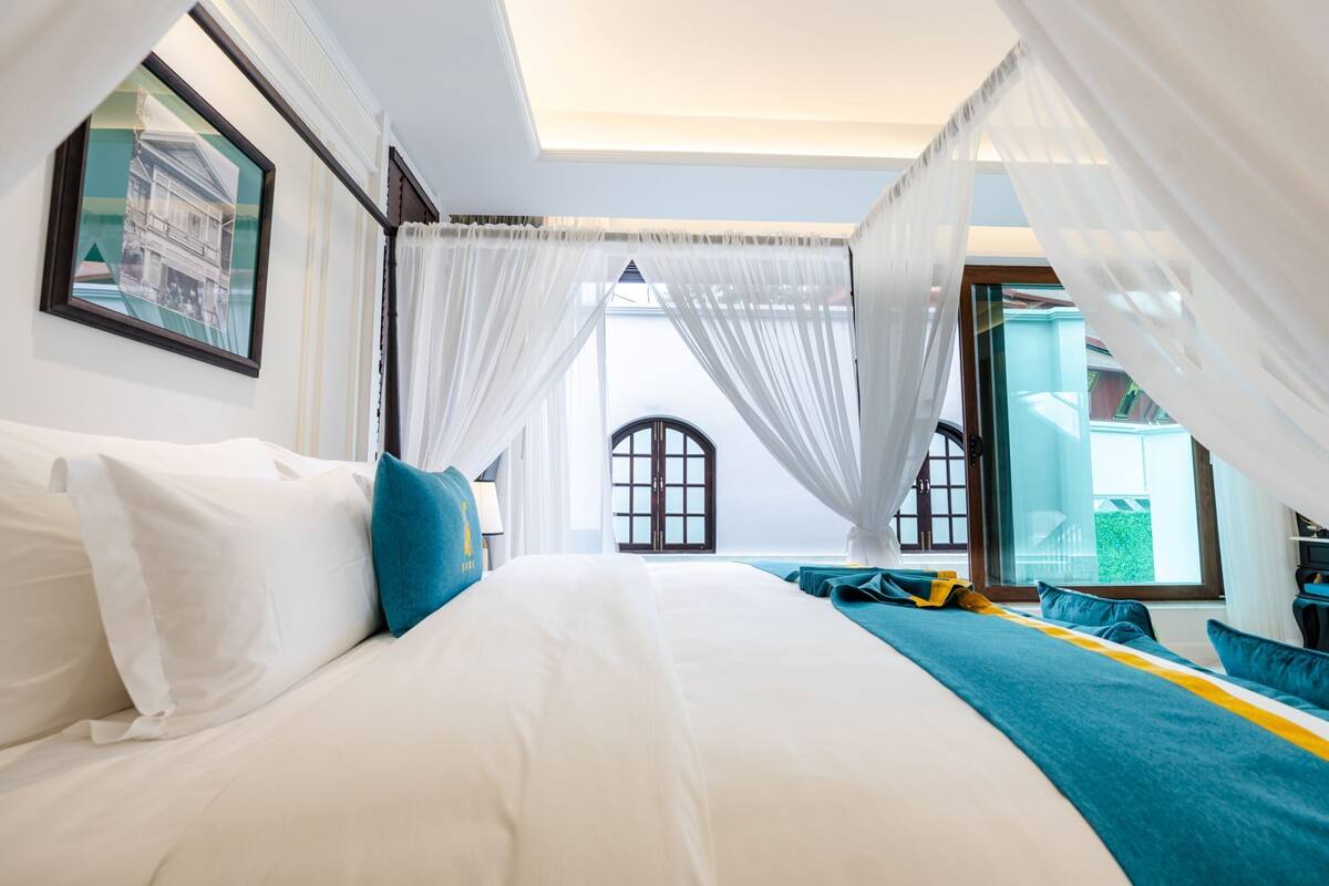 Une chambre d’hôtel avec un grand lit, des rideaux blancs et une vue sur l’extérieur.