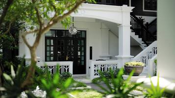 Un edificio blanco con una puerta negra, barandillas blancas y una escalera.