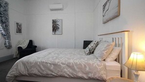 Et soveværelse med seng, natbord, lampe og billedkunst på væggene.