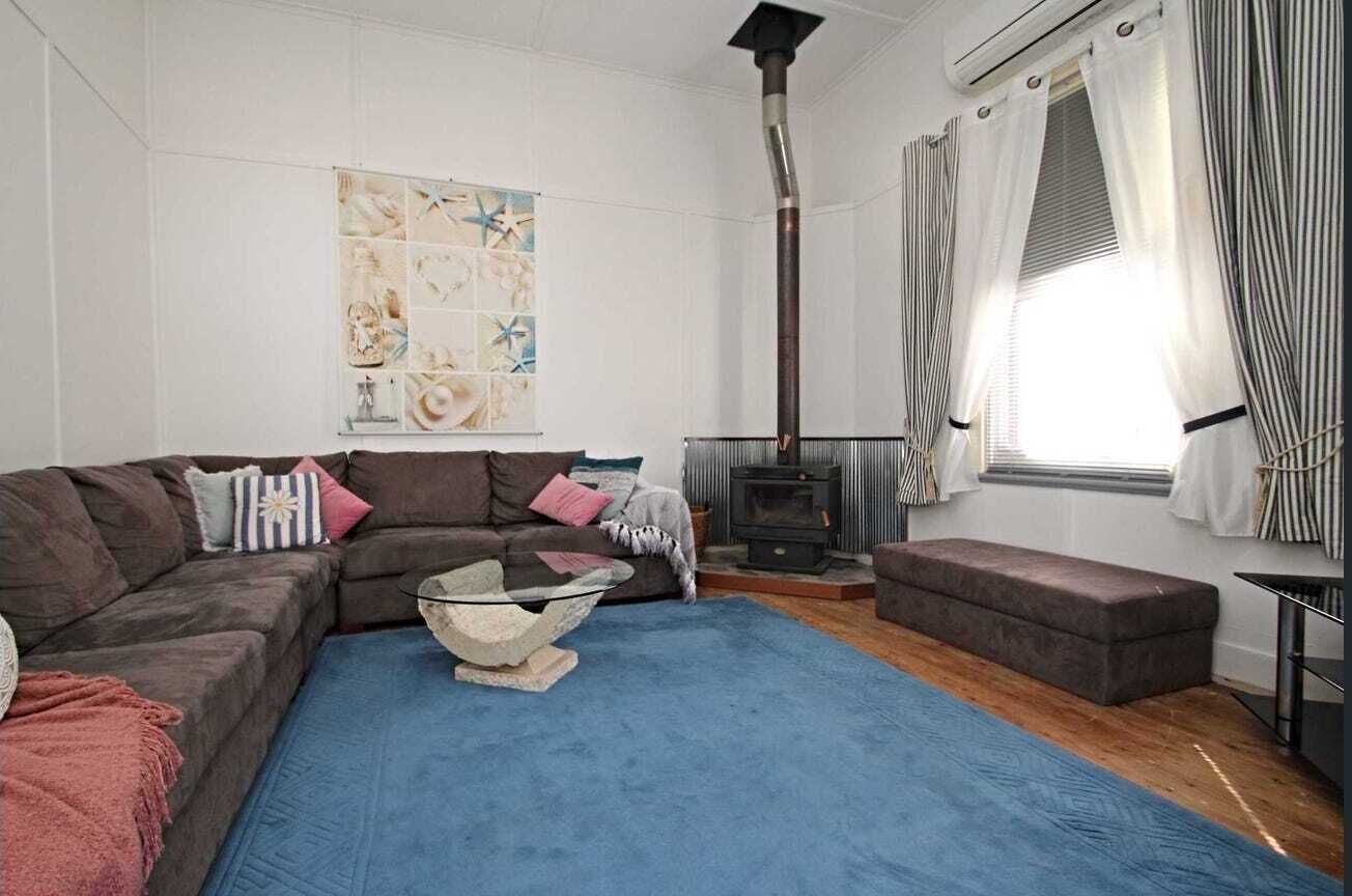A cozy living room with a sectional sofa, a blue rug, a fireplace, and a decorative wall piece.