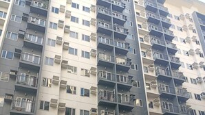 A multi-story residential building with balconies, air conditioning units, and a gated entrance. - Fabulous 2-bedroom condo unit in Quezon (Quezon)