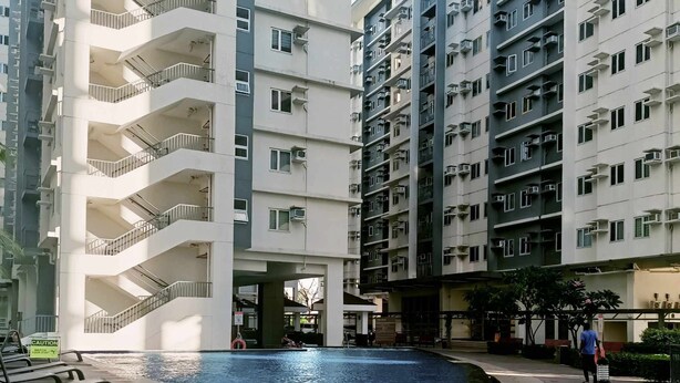 A residential building with multiple balconies, a swimming pool, and a staircase leading to the entrance. - Fabulous 2-bedroom condo unit in Quezon (Quezon)