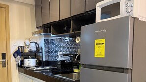 Una cocina moderna con microondas integrado, electrodomésticos de acero inoxidable y encimera negra.