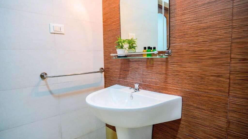 Un baño con un lavamanos blanco, un espejo y una pared de madera.