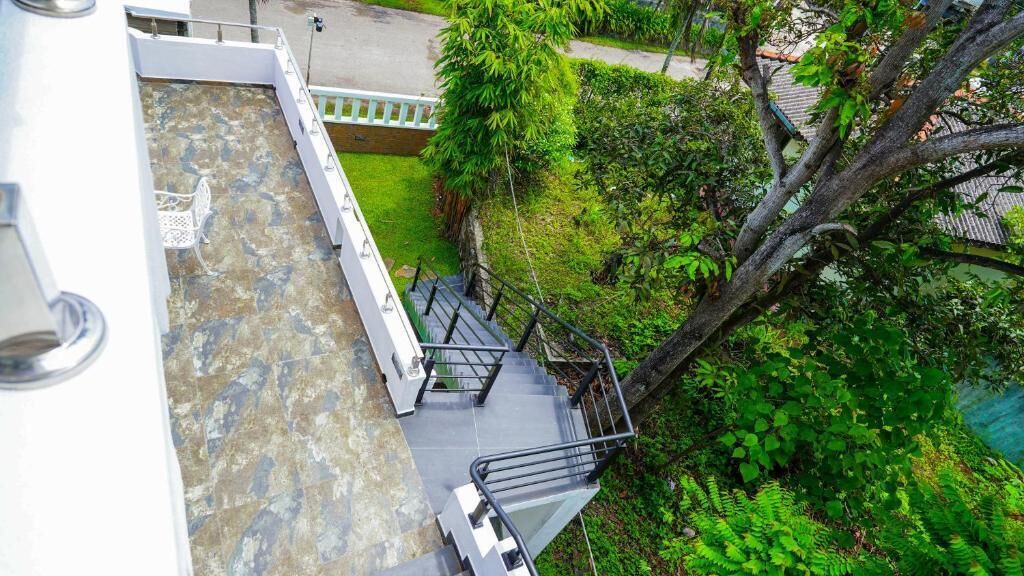 Un escalier menant à une terrasse sur le toit, dotée d’un sol en pierre et de rampes en métal.