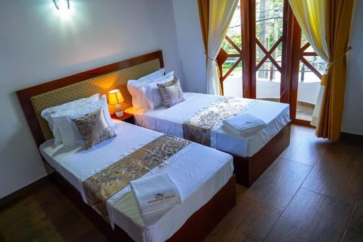 Ein Hotelzimmer mit zwei Betten, einem Nachttisch mit Lampe und Blick durch eine Glastür.