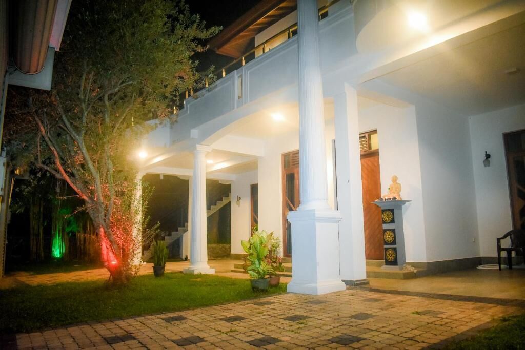 A well-lit outdoor area with a covered walkway, columns, and a statue.