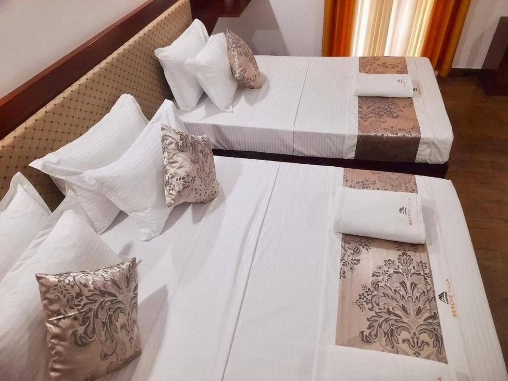 Two neatly made beds with white linens and decorative pillows.