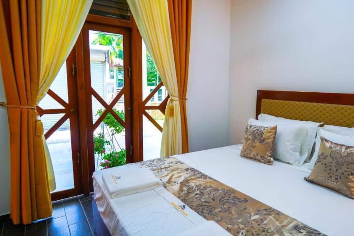 Ein Hotelzimmer mit Bett, Vorhängen und Blick durch eine Tür.