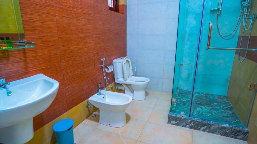 A bathroom with a sink, bidet, toilet, and glass shower enclosure.