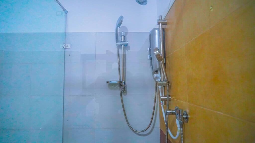 A shower with a handheld showerhead and a wall-mounted faucet.
