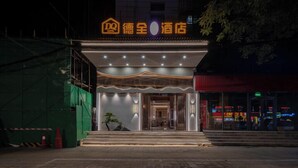 Entrada de hotel con fachada moderna, acceso visible y un letrero con caracteres chinos.