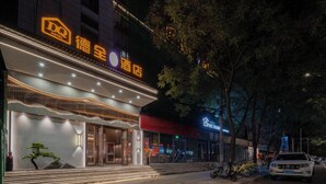 Un hotel con fachada moderna, señalización iluminada y una entrada bien iluminada.