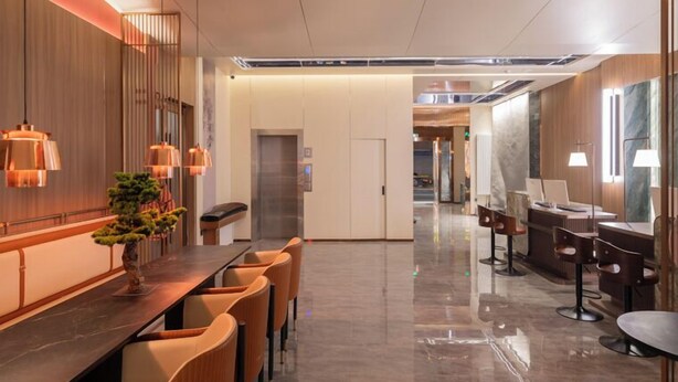 Un moderno vestíbulo de hotel con un mostrador de recepción alargado, zona de estar y vista despejada del interior.