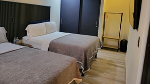 A hotel room with two beds, a wardrobe, a shower area, and a mounted TV. - Double room 04 with 2 double beds, air conditioning, private bathroom (San Salvador)