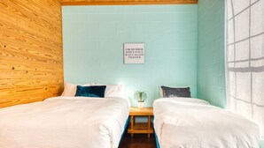 A room with two beds, a wooden headboard, a light blue brick wall, and a framed quote on the wall. - Crystal Clear Frio River - Private Waterfront House - Room for the Family (Concan)