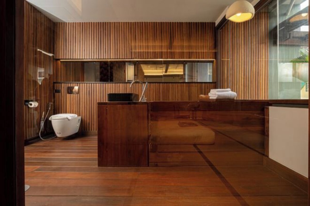 A modern bathroom with wooden paneling, a large mirror, and a built-in sink.