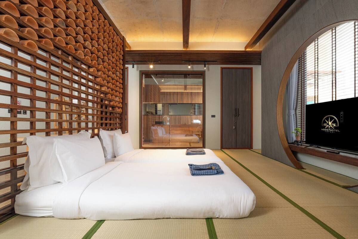 A modern hotel room with a large bed, a TV, and a view of the city.
