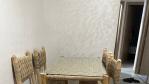 Une table à manger avec des chaises en osier et un tapis à motifs géométriques.