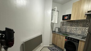 Une cuisine compacte équipée d’un four à micro-ondes, d’un lave-linge et d’un radiateur.