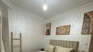 Une chambre à coucher comprenant un lit, une table de chevet, une échelle en bois et des œuvres d’art décoratives accrochées au mur.