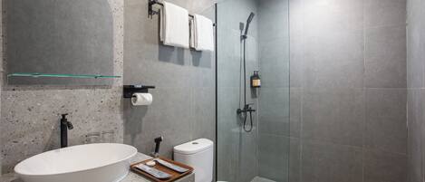 Une salle de bain moderne avec une baignoire sur pieds, des toilettes, une douche à parois de verre et un grand miroir.