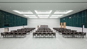 A conference room with multiple tables and chairs, a podium, and a stage with a backdrop. - Casa De Lani Resort & Convention (Baturaden)