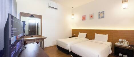 A hotel room with two beds, a TV, a desk, and a mirror.