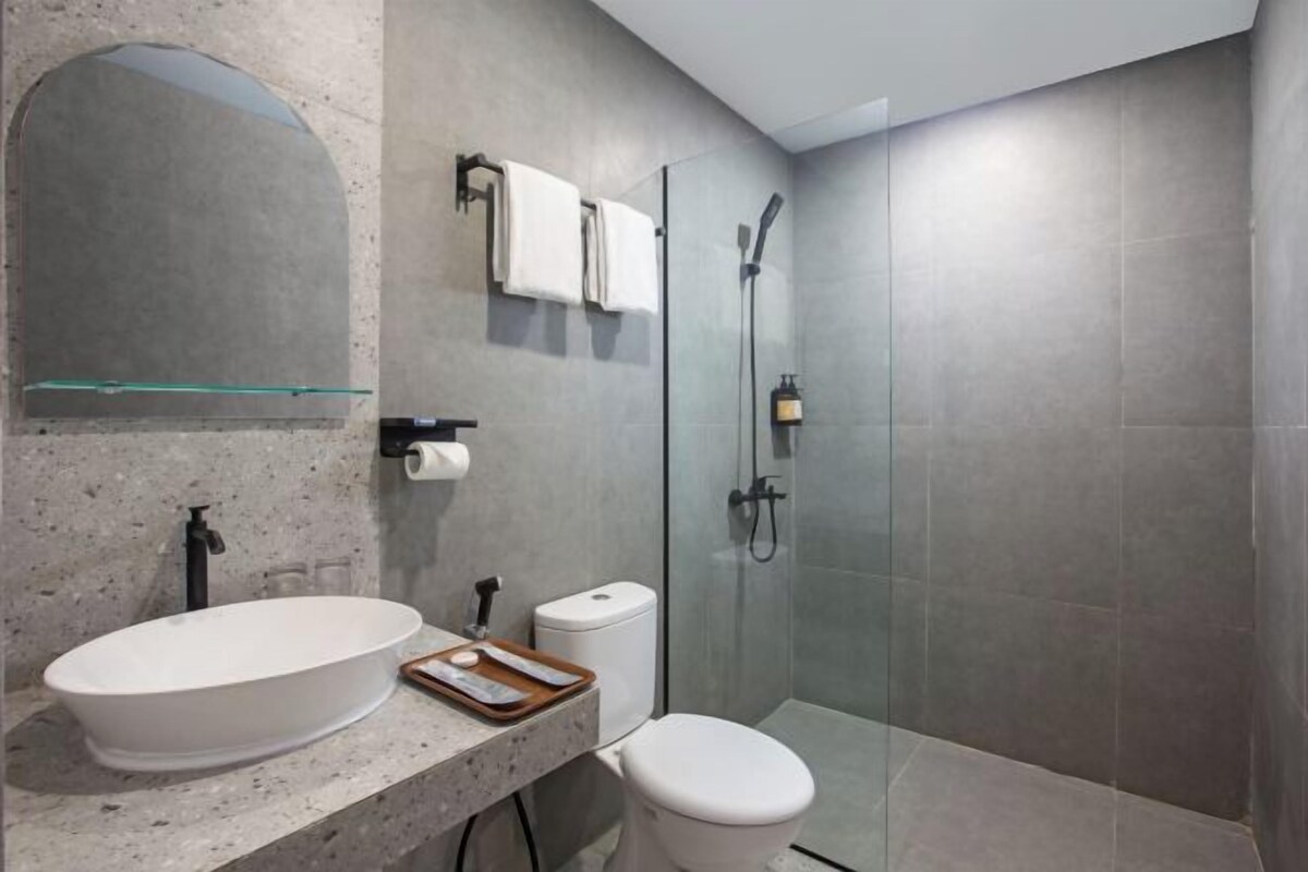 Een moderne badkamer met een vrijstaand bad, toilet en een douche met glazen wanden.