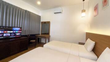 A hotel room with two beds, a desk, a television, and a mirror.