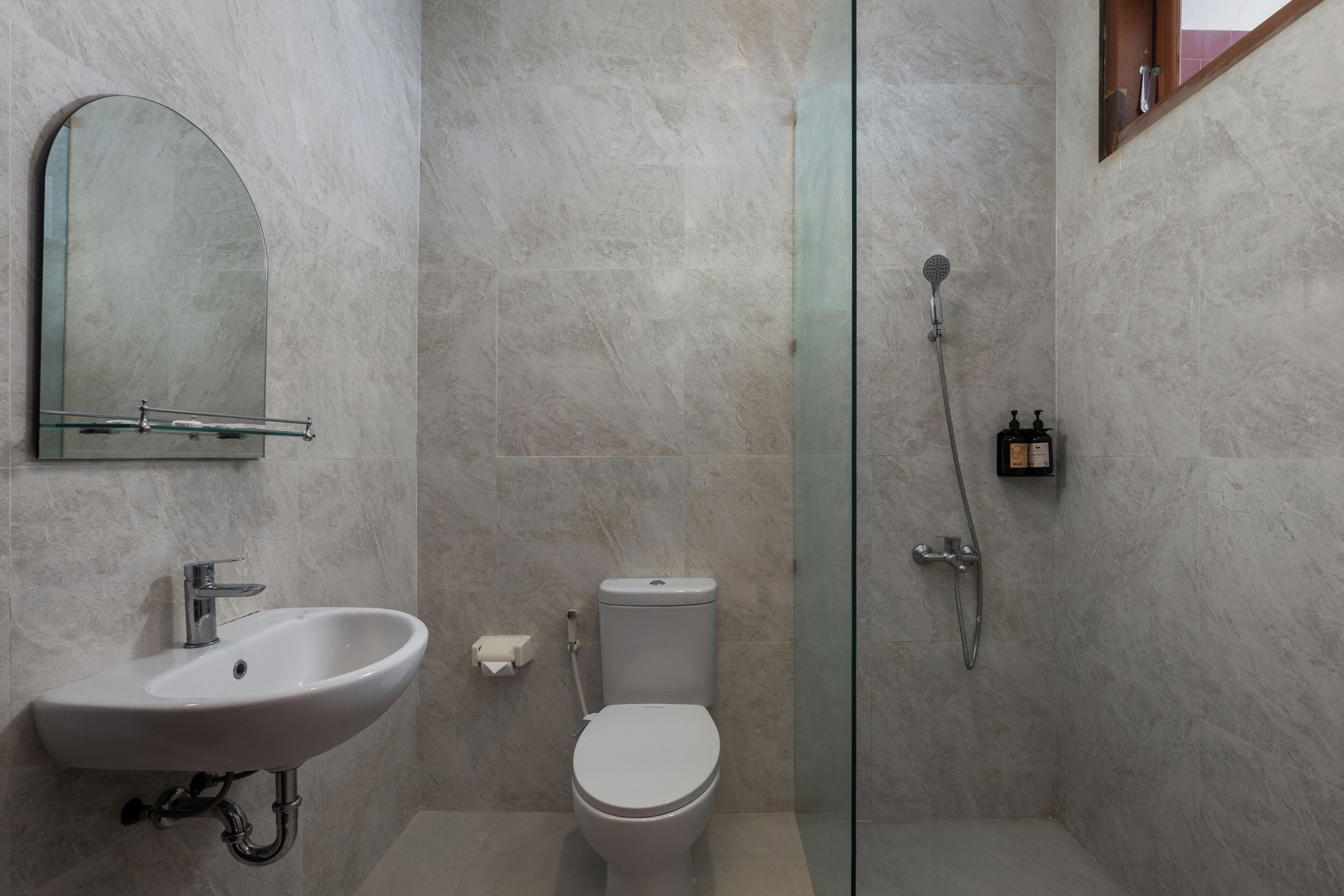 Un baño moderno con lavamanos, inodoro y ducha con mampara de vidrio.