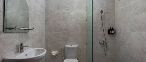Un baño moderno con lavamanos, inodoro y ducha con mampara de vidrio.