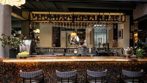A bar area with a bartender, a menu, and a variety of bottles and glasses. - The Kin Hotel (Mumbai)