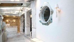 A hallway with marble flooring, a reception desk, and a wall-mounted mirror. - The Kin Hotel (Mumbai)