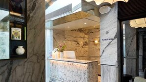 A lobby with marble flooring, a reception desk, and a check-in counter. - The Kin Hotel (Mumbai)