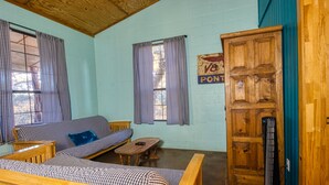 A room with a checkered sofa, a wooden table, and a cabinet. - Beautiful Secluded Cabin in the Woods - Second Wind Ranch (Leakey)