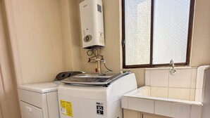 A laundry area with a washing machine, dryer, and a sink with a window above.