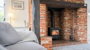 A cozy living room with a brick fireplace, a sofa, and a lamp. - Hollybank Cottage, Ufford (Ufford)