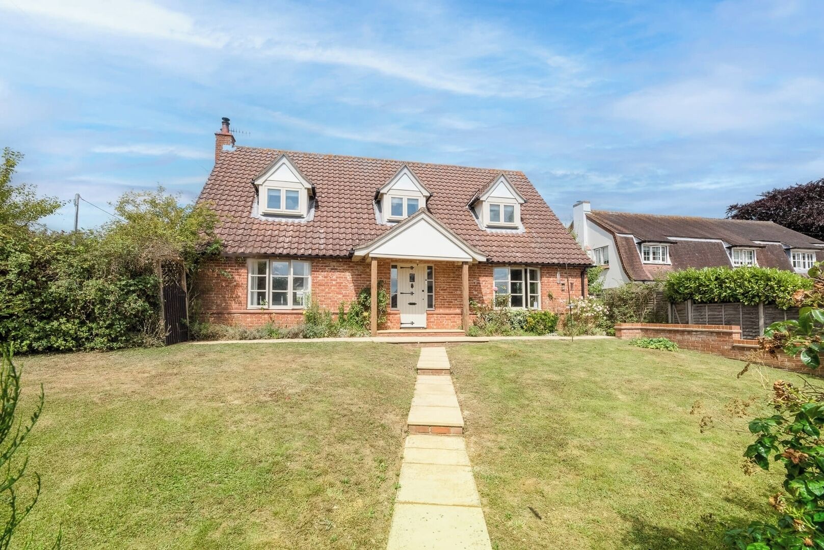 A two-story house with a tiled roof, a front porch, and a well-maintained lawn.