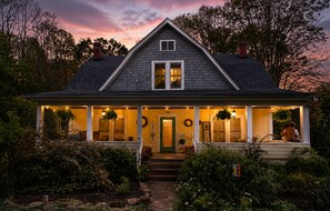 A two-story house with a porch, a front door, and a number '144' on the wall.