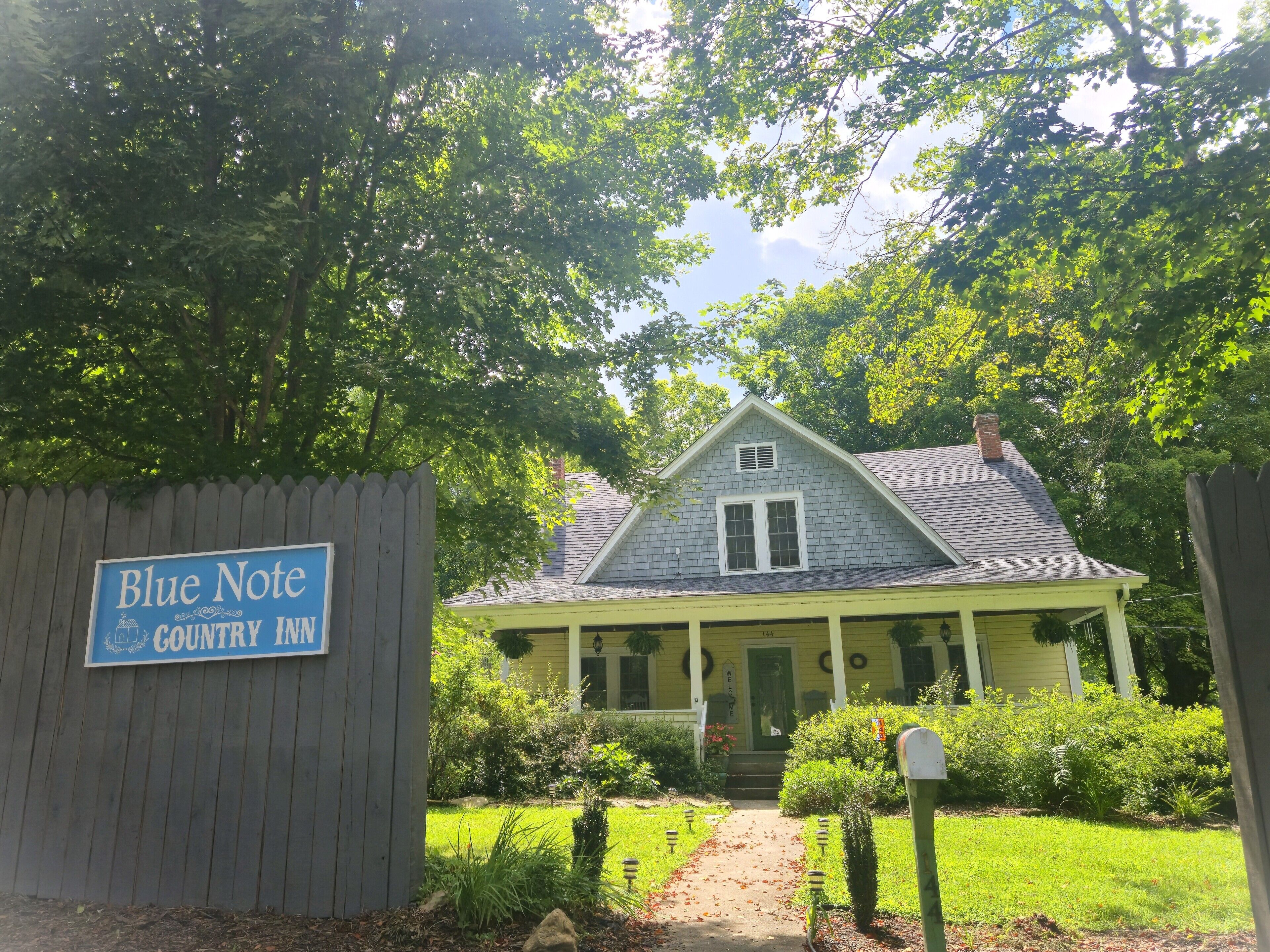 A country inn with a wooden fence, a signboard, and a well-maintained garden.